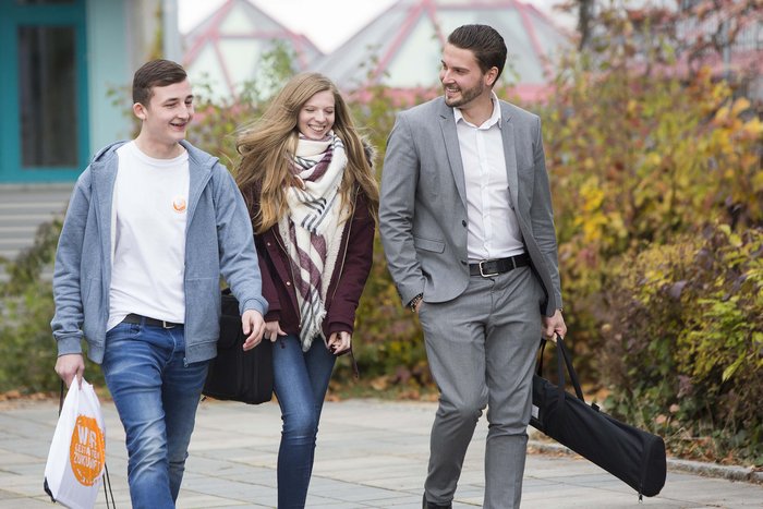 Drei lächelnde Schüler laufen nebeneinander