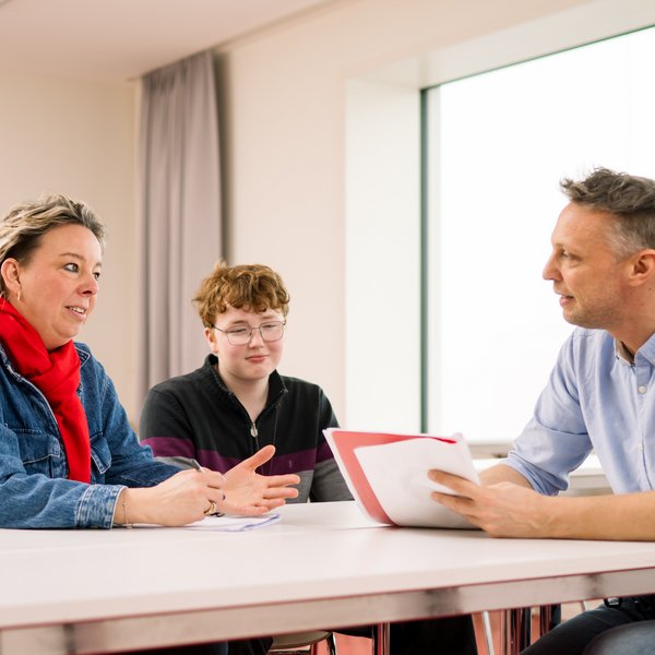 Lehrkraft spricht mit Mutter und Sohn. 