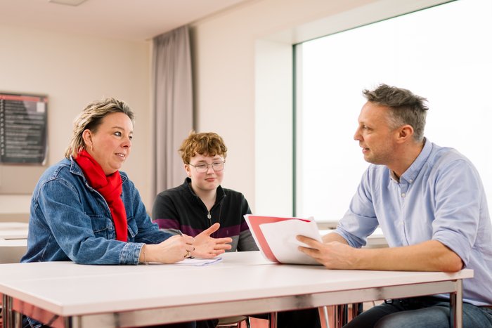 Lehrkraft spricht mit Mutter und Sohn. 