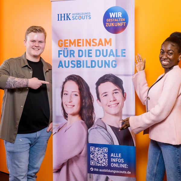 Zwei Personen stehen vor einem Roll-up mit der Aufschrift "Gemeinsam für die duale Ausbildung"