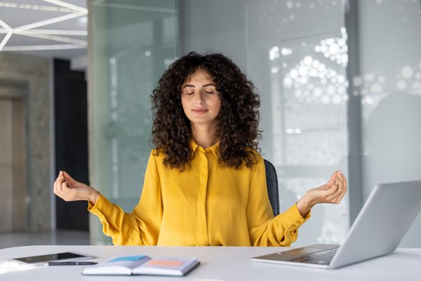 Meditierende Frau am Schreibtisch. Foto: Adobe Stock