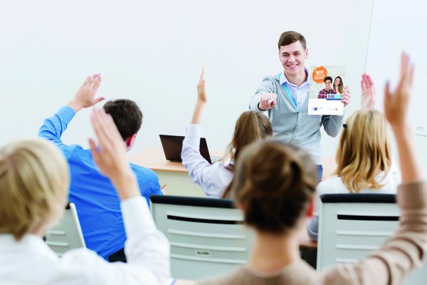 Schüler hält Flyer in der Hand und zeigt auf Personen die sich melden 