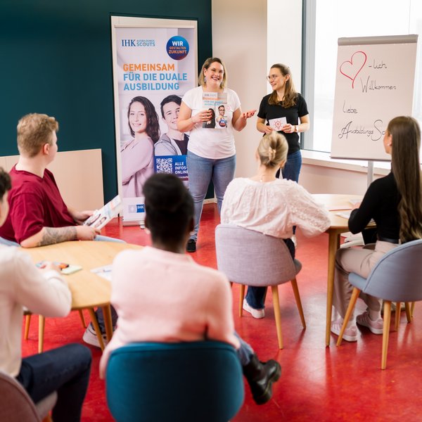 Zwei Regionalkoordinatorinnen führen eine Schulung der AusbildungsScouts durch und stehen vor der Gruppe und erklären. 