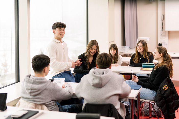 Azubi arbeitet mit Kleingruppe im Klassenzimmer