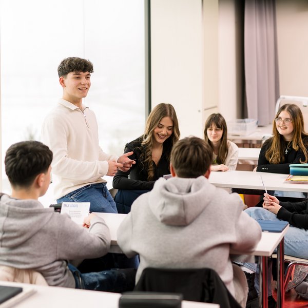 Azubi arbeitet mit Kleingruppe im Klassenzimmer
